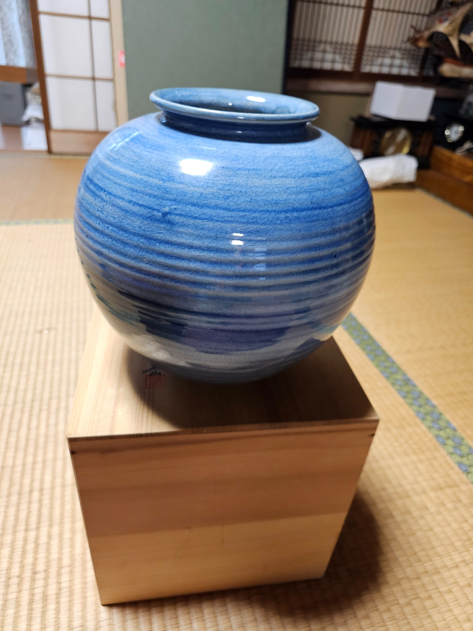 Blue glazed ceramic jar on a wood box.